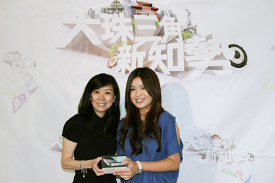 《大珠三角新知势》节目的总策划庄漪小姐(左)，向范嘉贤小姐颁iPhone4手机一部。