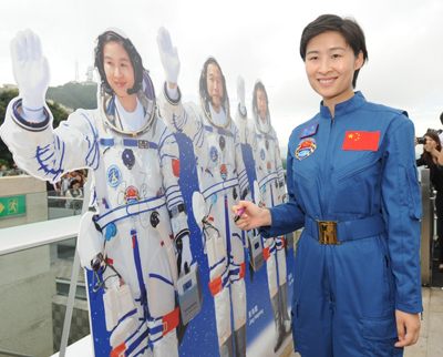 中国首名女航天员刘洋成为市民关注的焦点。她在参观山顶时，为自己的纸板公仔签名。